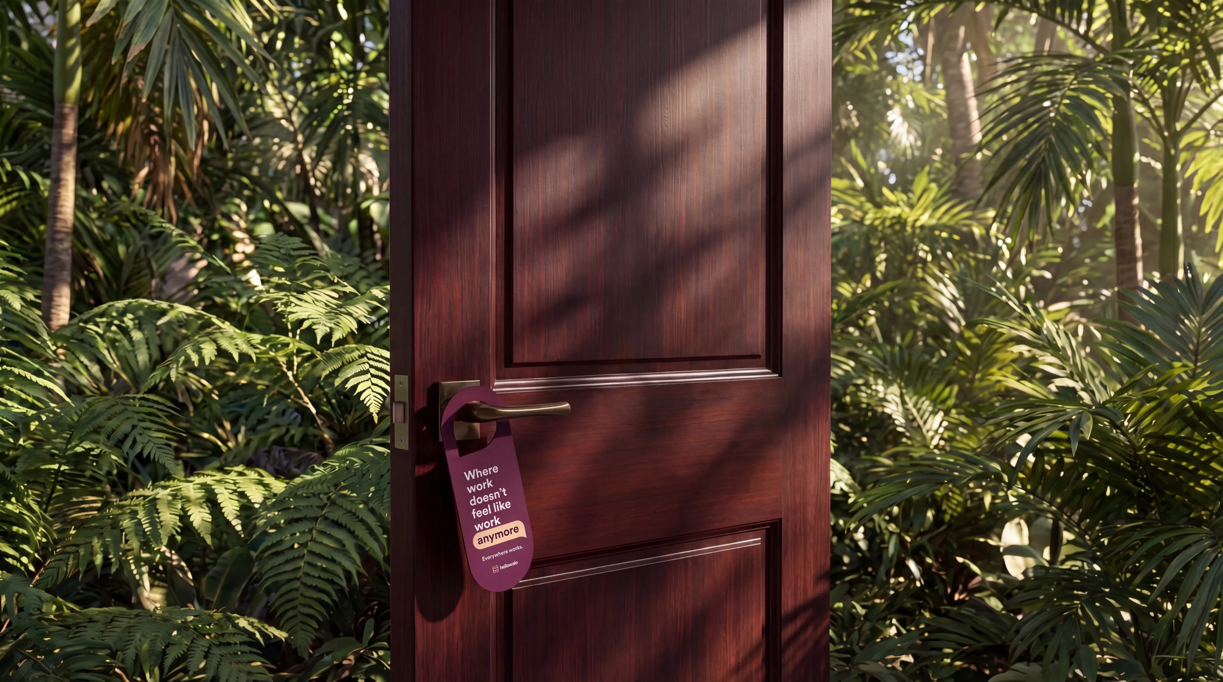 A hotel-style door hanger reading 'Where work doesn't feel like work anymore' on a dark wood door surrounded by jungle greenery